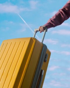 Valigia gialla pronta per un viaggio, con la mano che la tiene saldamente sotto un cielo sereno. Rappresenta la connettività globale e un'esperienza di viaggio senza preoccupazioni per la connessione.